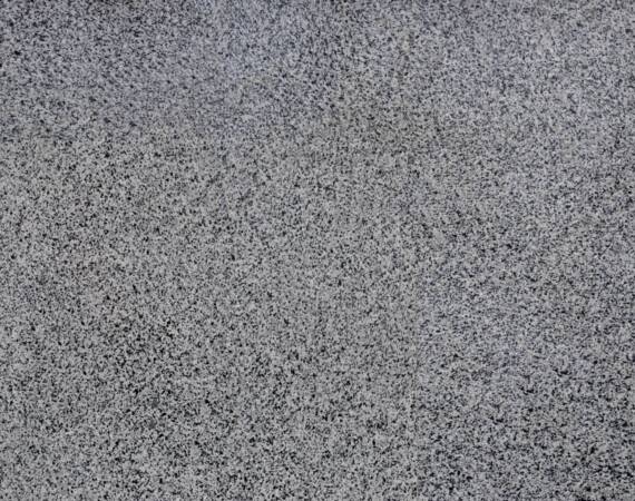 The texture of solid granite tiles. Hard and slippery gray granite surface with a relief discharge when exposed to sunlight